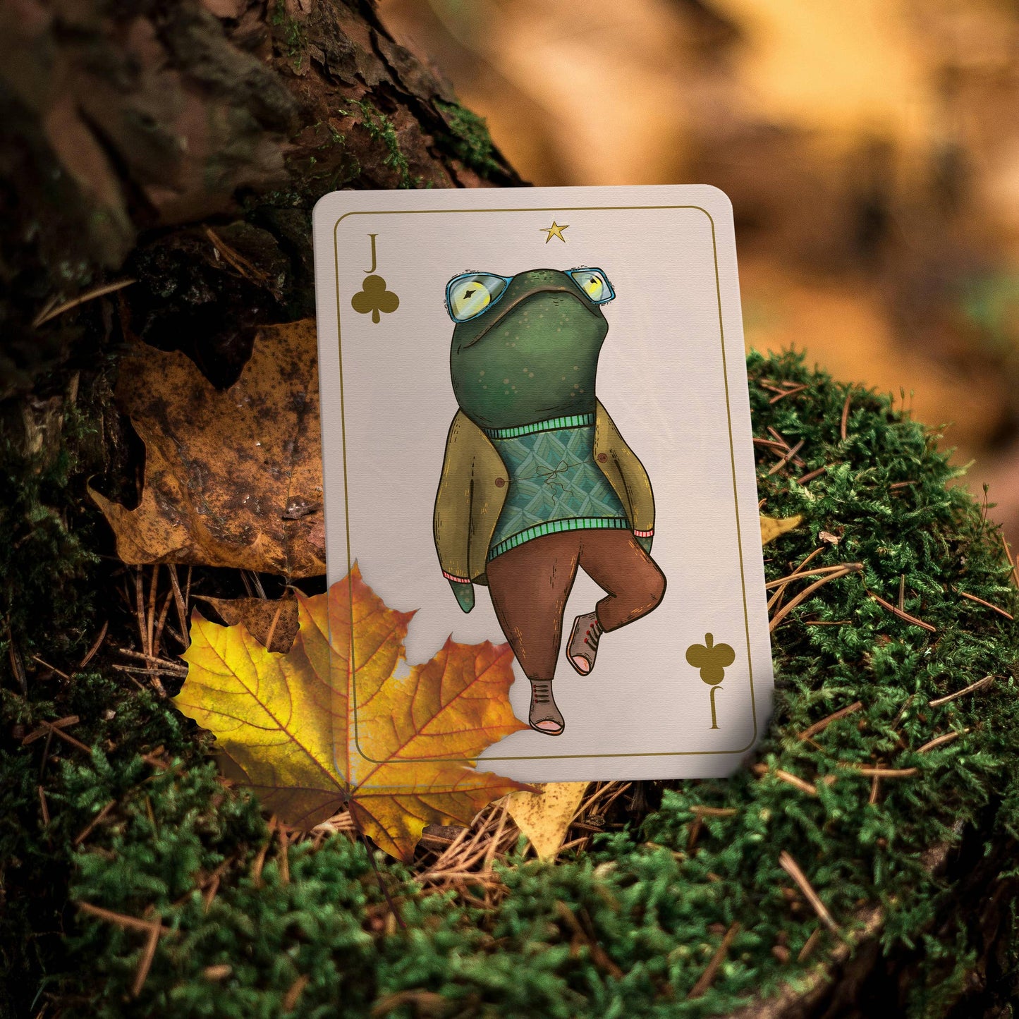 Playing card with a frog illustration on a natural background with leaves and moss