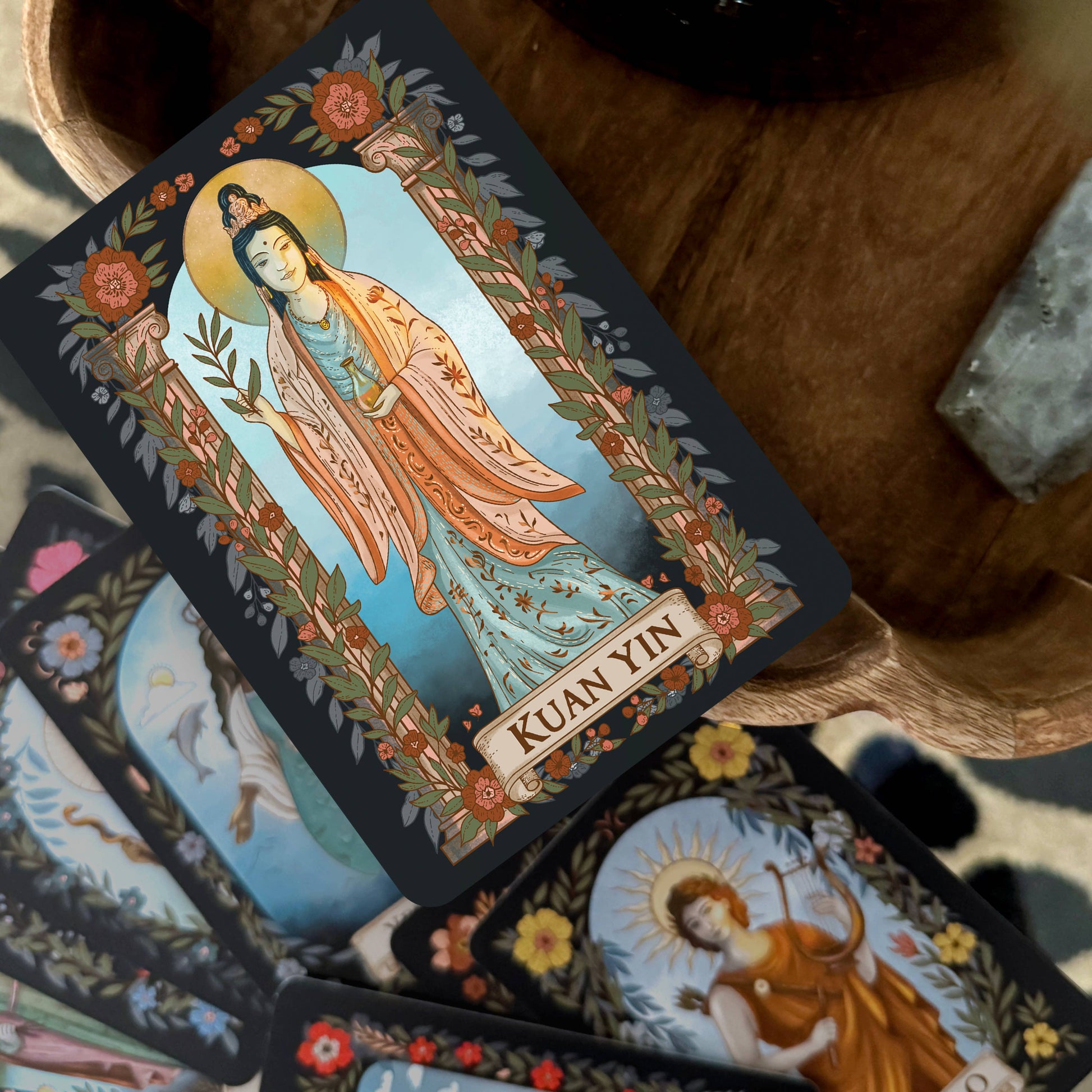 Card featuring Kuan Yin with decorative elements on a wooden surface