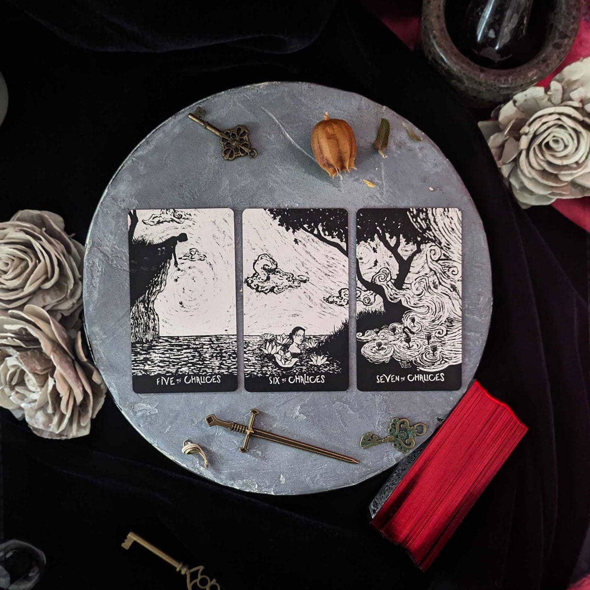 Triptych tarot card set on a round stone surface with decorative items.