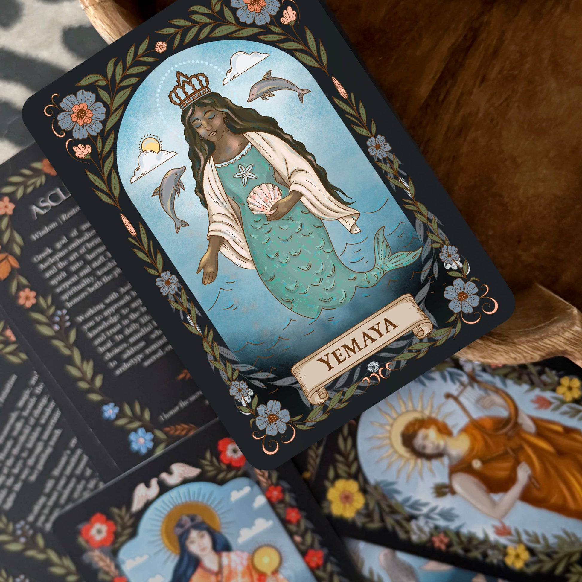 Card featuring a mermaid-like figure with 'Yemaya' at the bottom, surrounded by decorative elements.