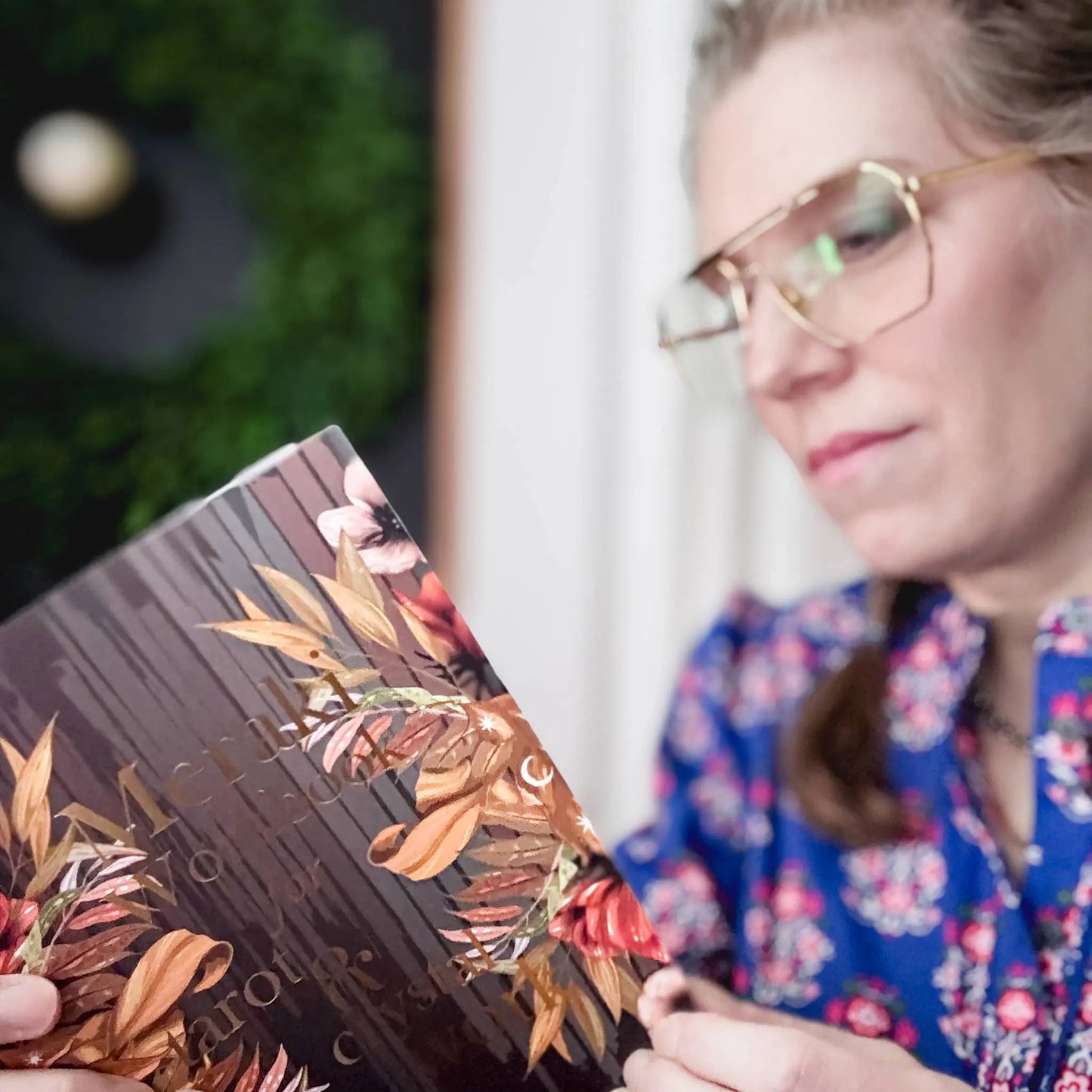 Person holding a makeup palette with floral design, blurred background Meraki workbook for tarot and crystal work