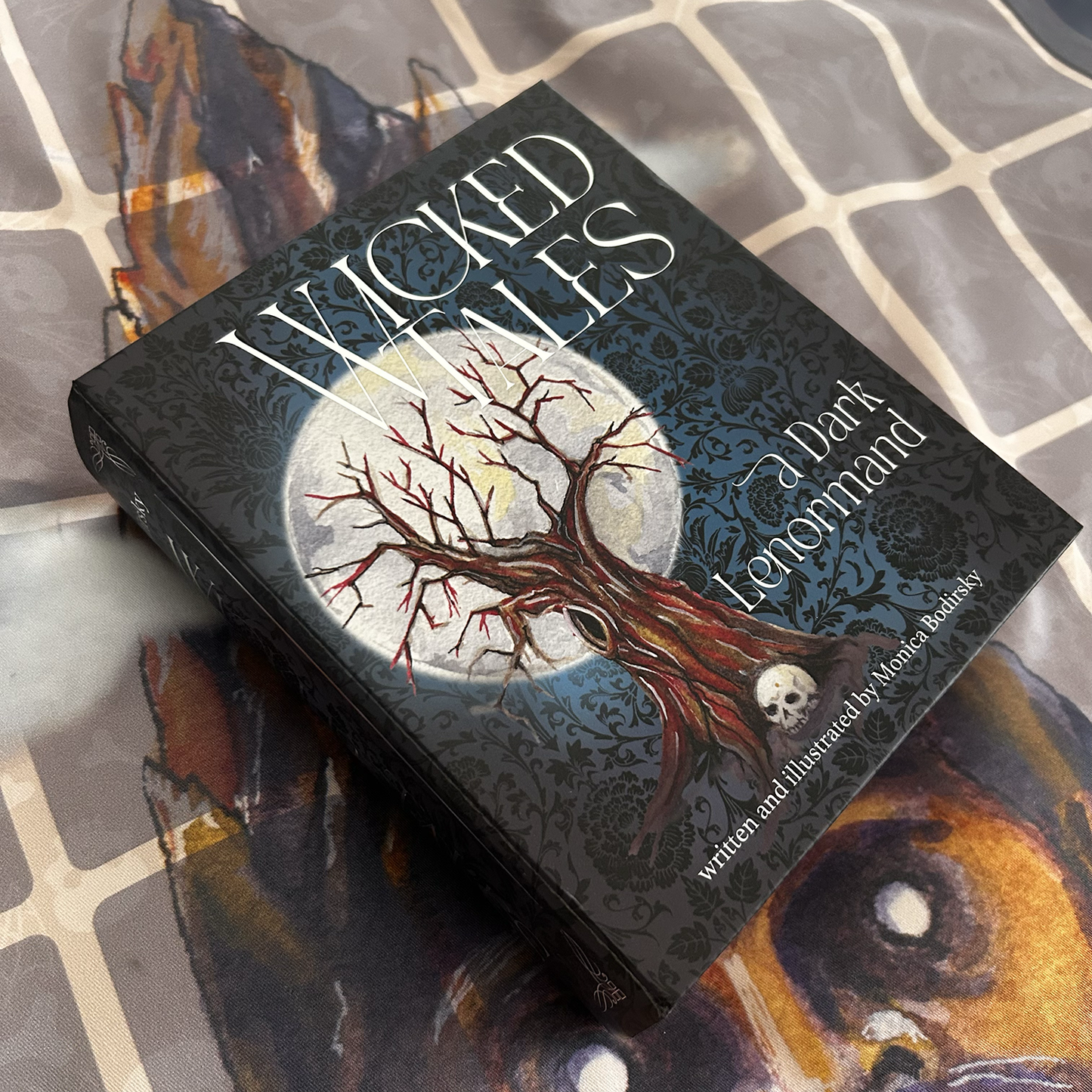 Card deck titled 'Wicked Tales: A Dark Lenormand' with a tree and moon design on a textured surface.