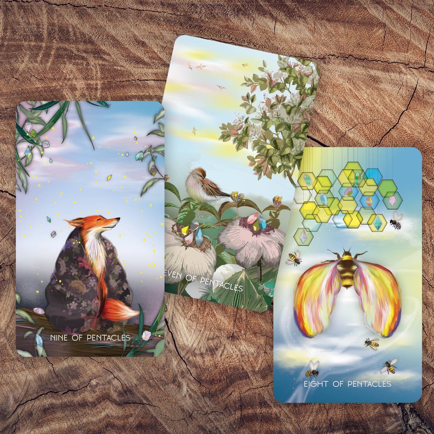 Three tarot cards with nature-themed illustrations on a wooden surface