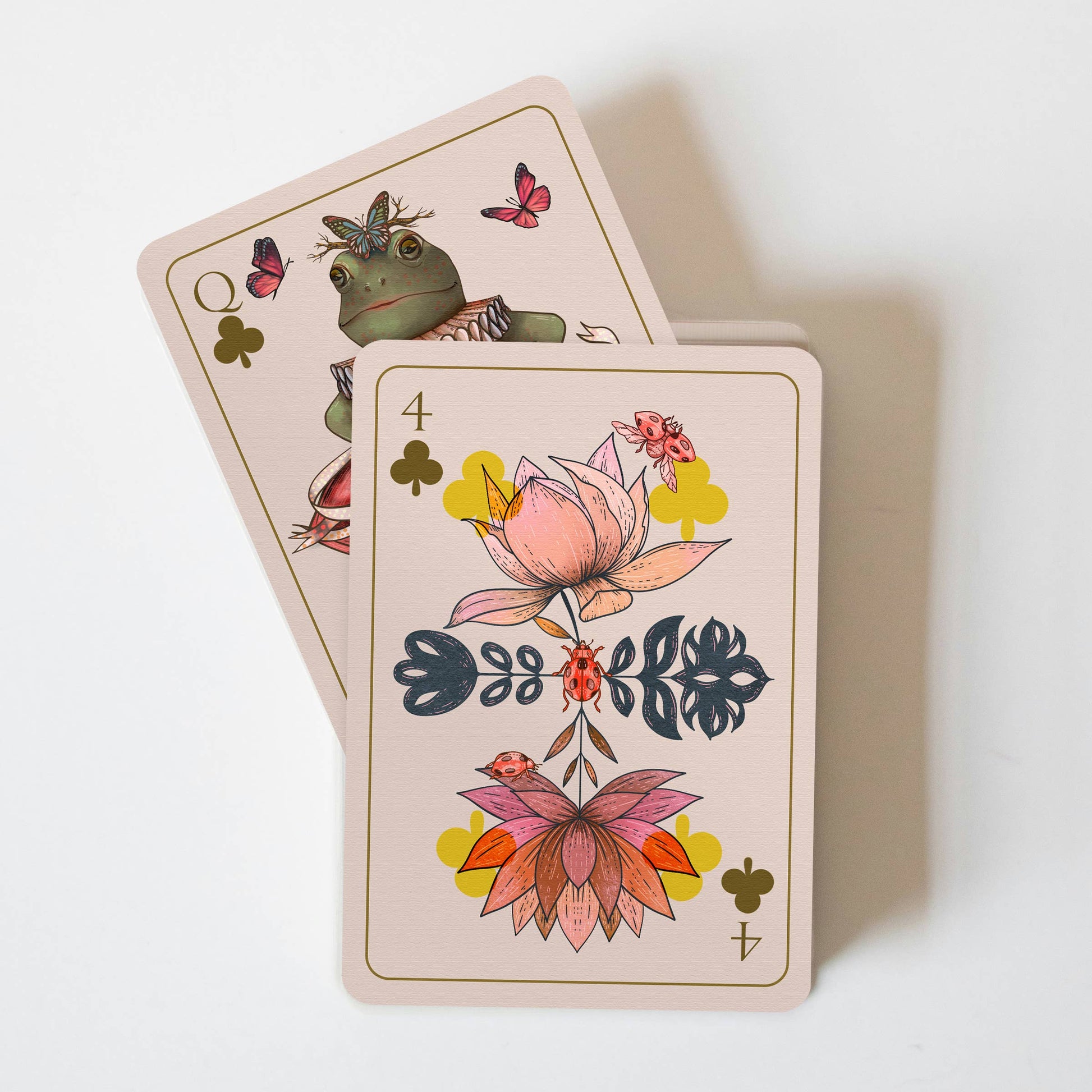 Two playing cards with floral and nature-themed designs on a white background