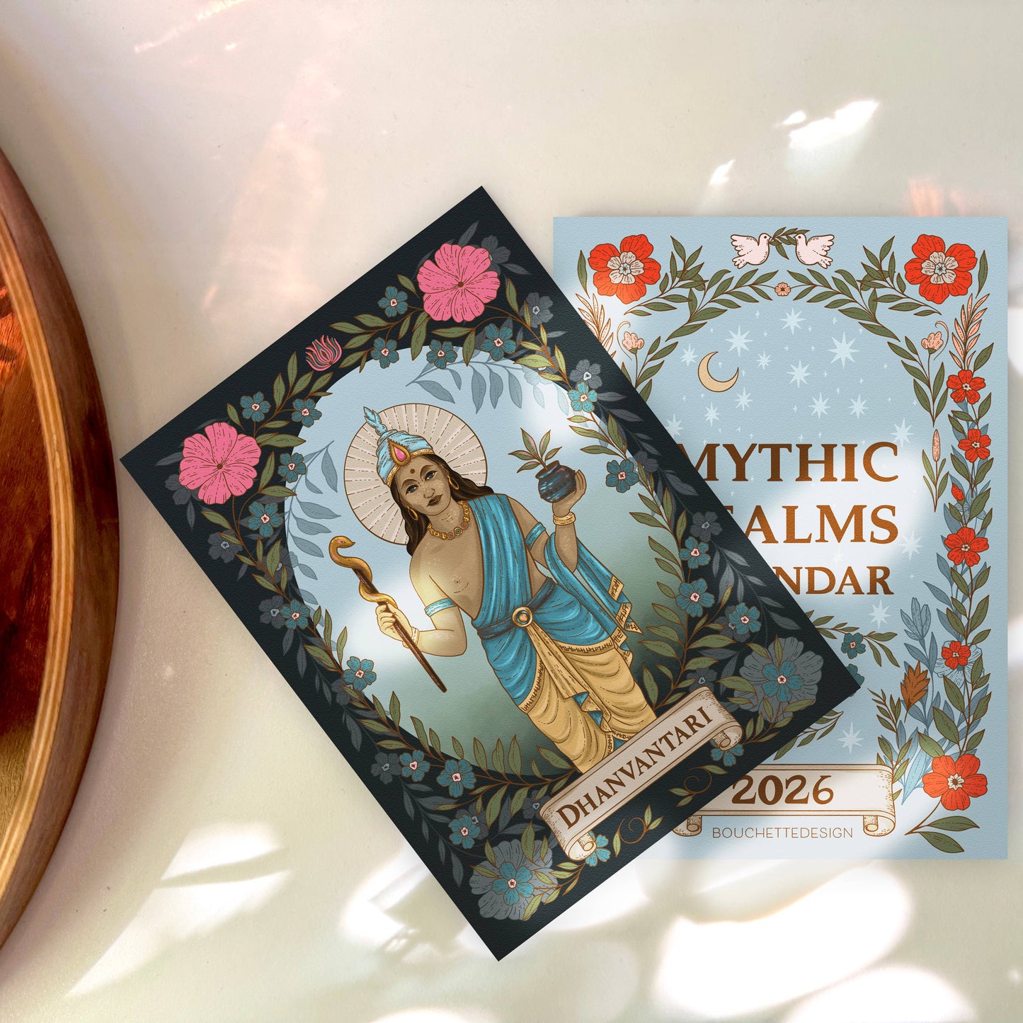 Two Mythic Palms calendar covers on a light surface with floral designs.