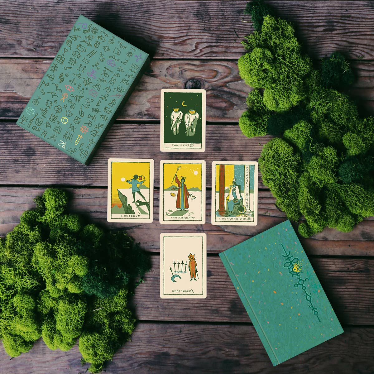 Image depicting tarot spread featuring the Green Glyphs card deck by James R Reads on wooden table and foliage