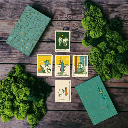 Image depicting tarot spread featuring the Green Glyphs card deck by James R Reads on wooden table and foliage