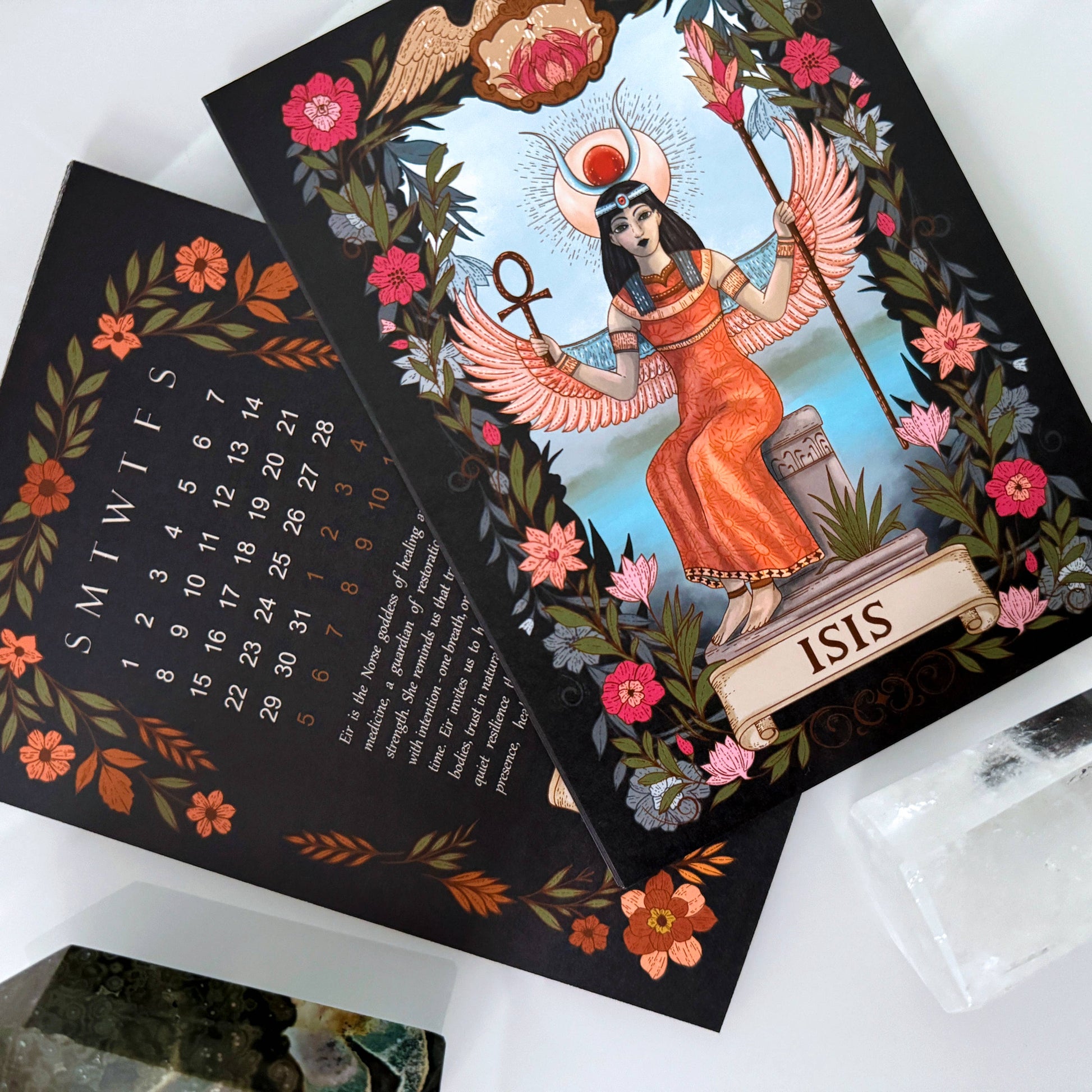 Decorative calendar with Isis illustration and floral design on a white surface
