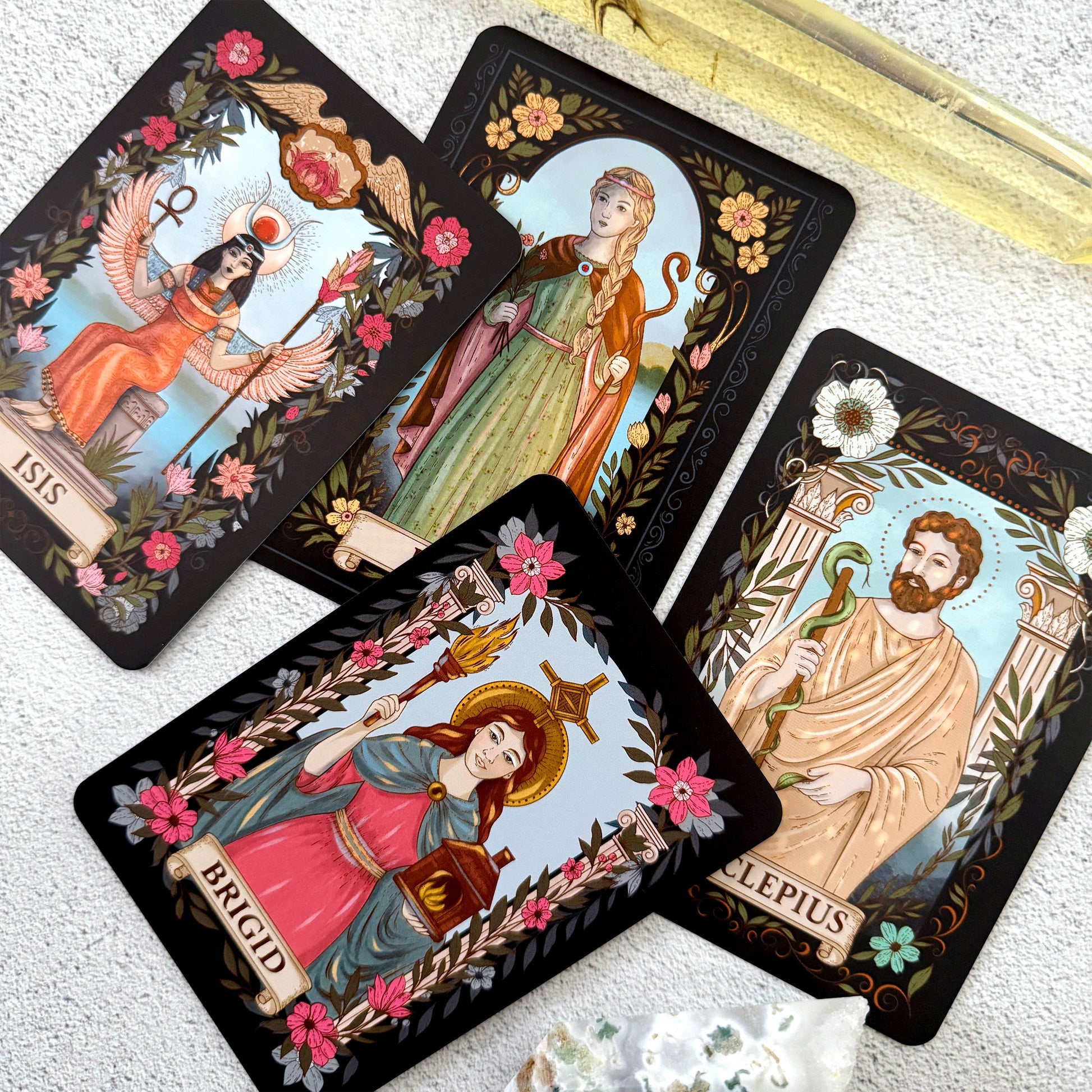 Four tarot cards with illustrated figures and floral decorations on a textured surface.