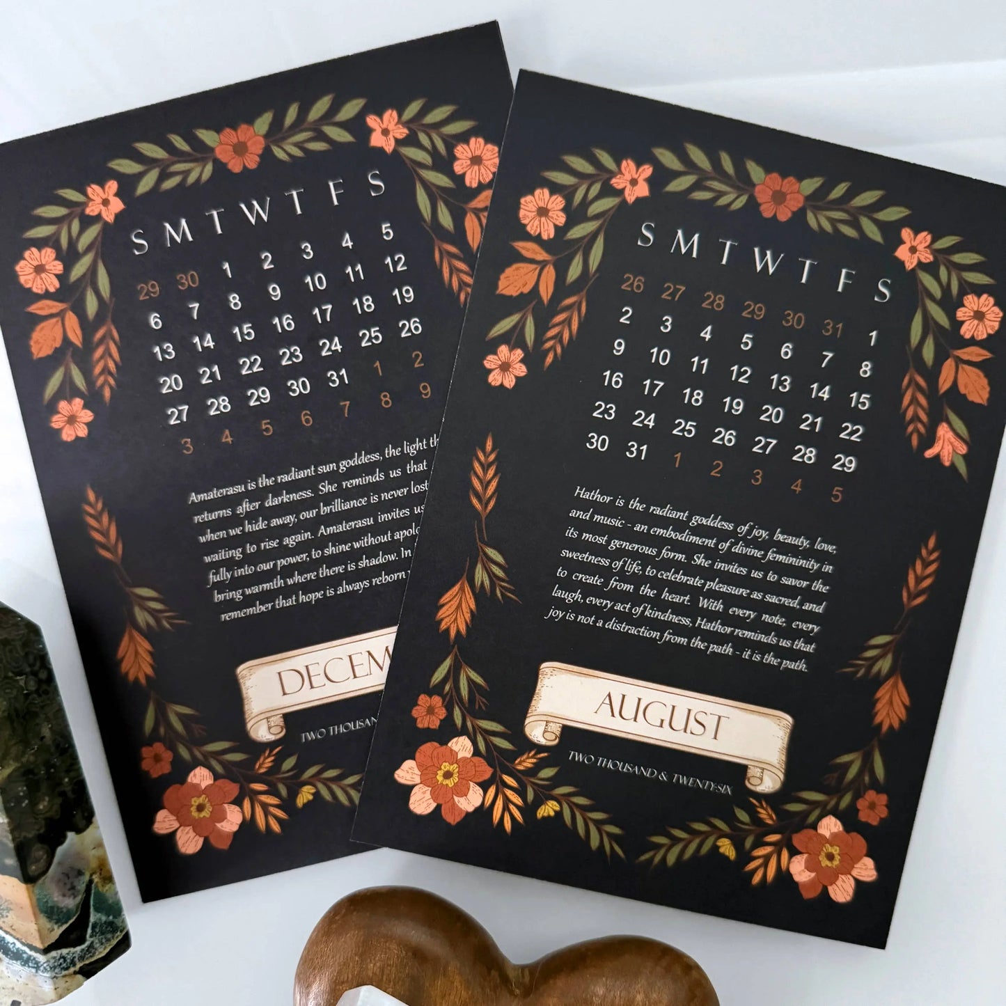Two decorative calendars for December and August with floral designs on a white surface.