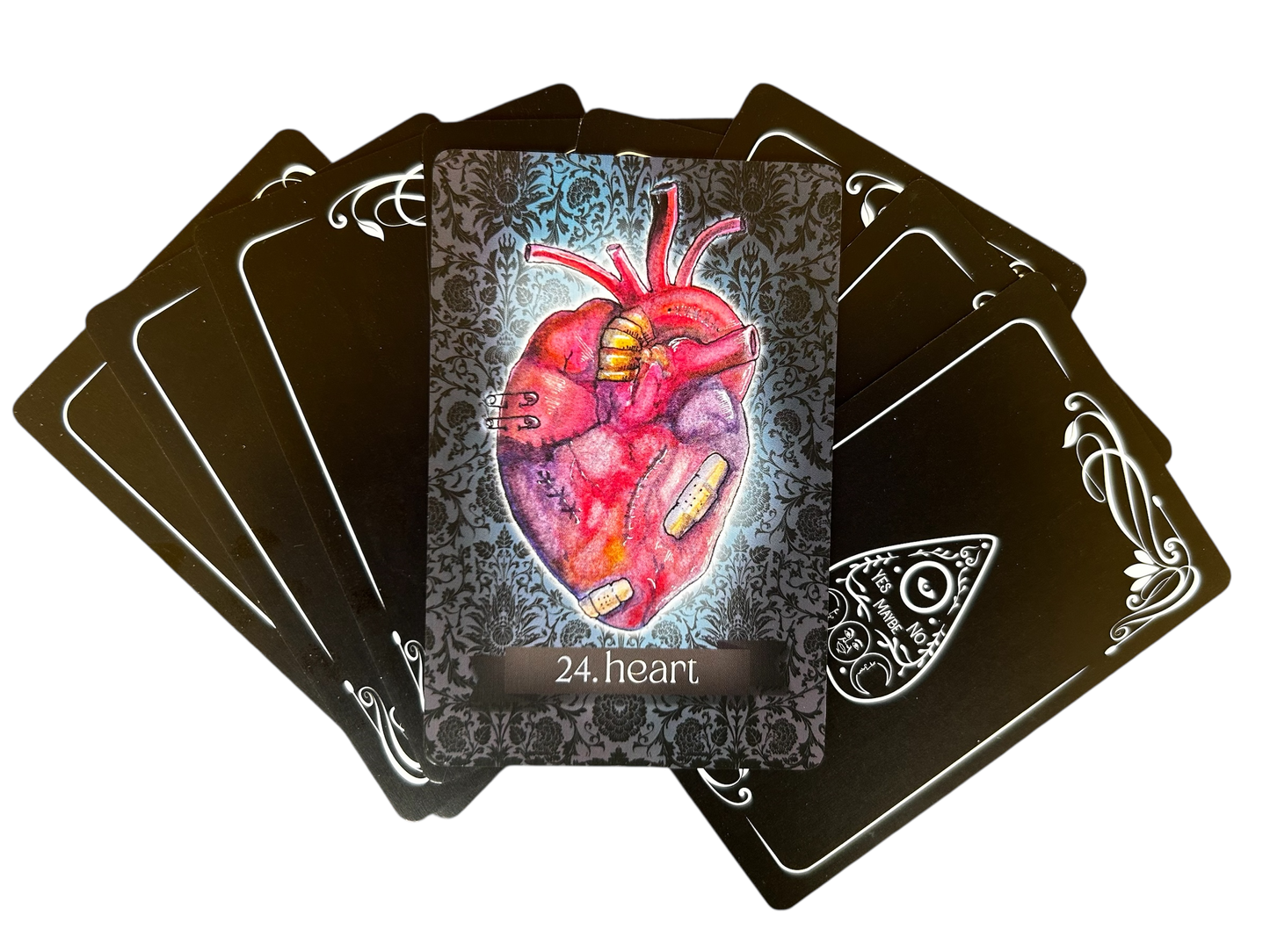 Playing card with a detailed illustration of a heart on a black card with ornate edges.