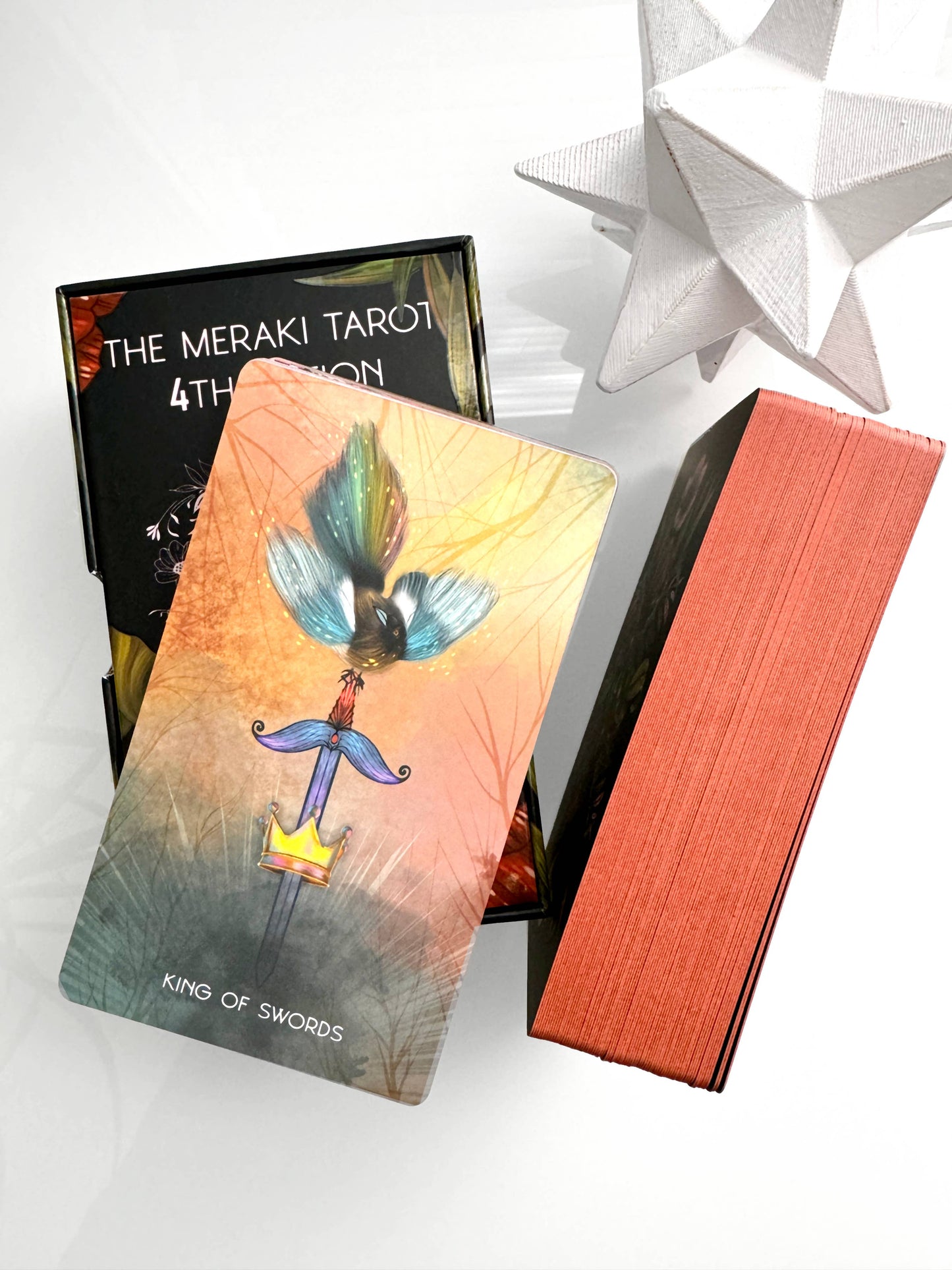 Tarot card with 'The Meraki Tarot' box and packaging on a white background