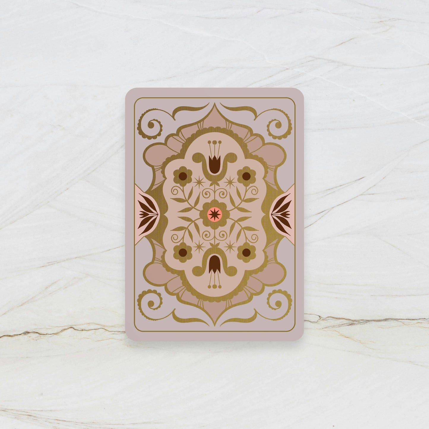 Decorative playing card with intricate gold and brown design on a white marble surface