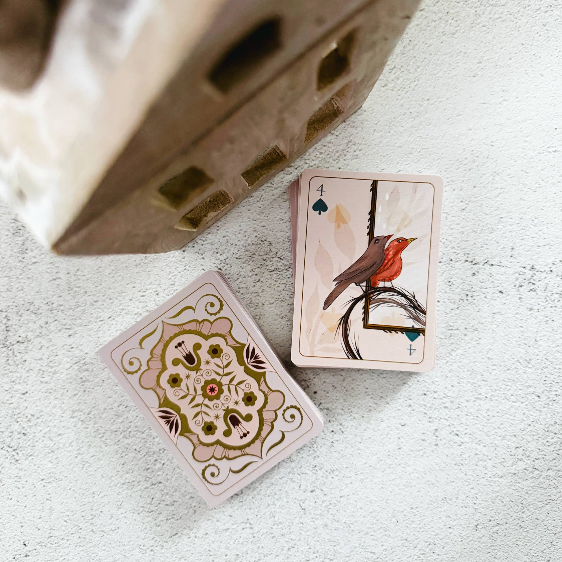 Two playing cards with intricate designs on a textured surface