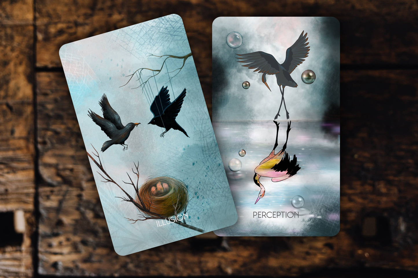 Two tarot cards with bird illustrations on a wooden surface