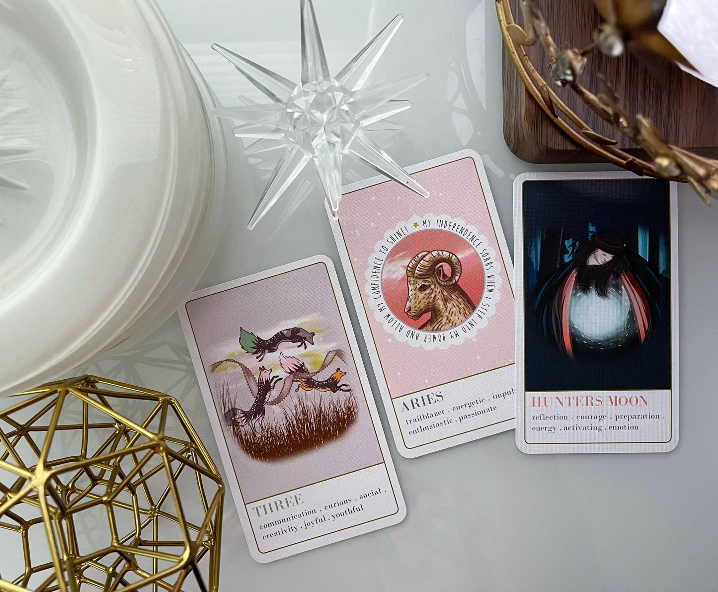 Wanderlust collection oracle deck Three tarot cards on a white surface with decorative elements.