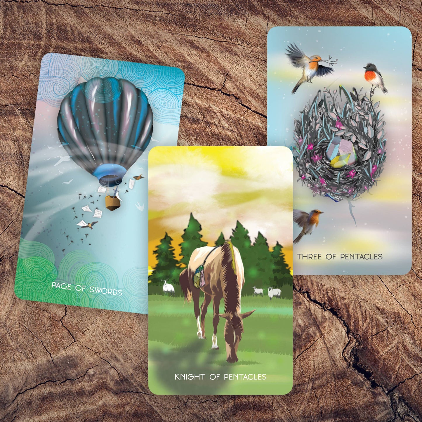 Three tarot cards on a wooden surface with hot air balloon, horse, and birds in a nest.