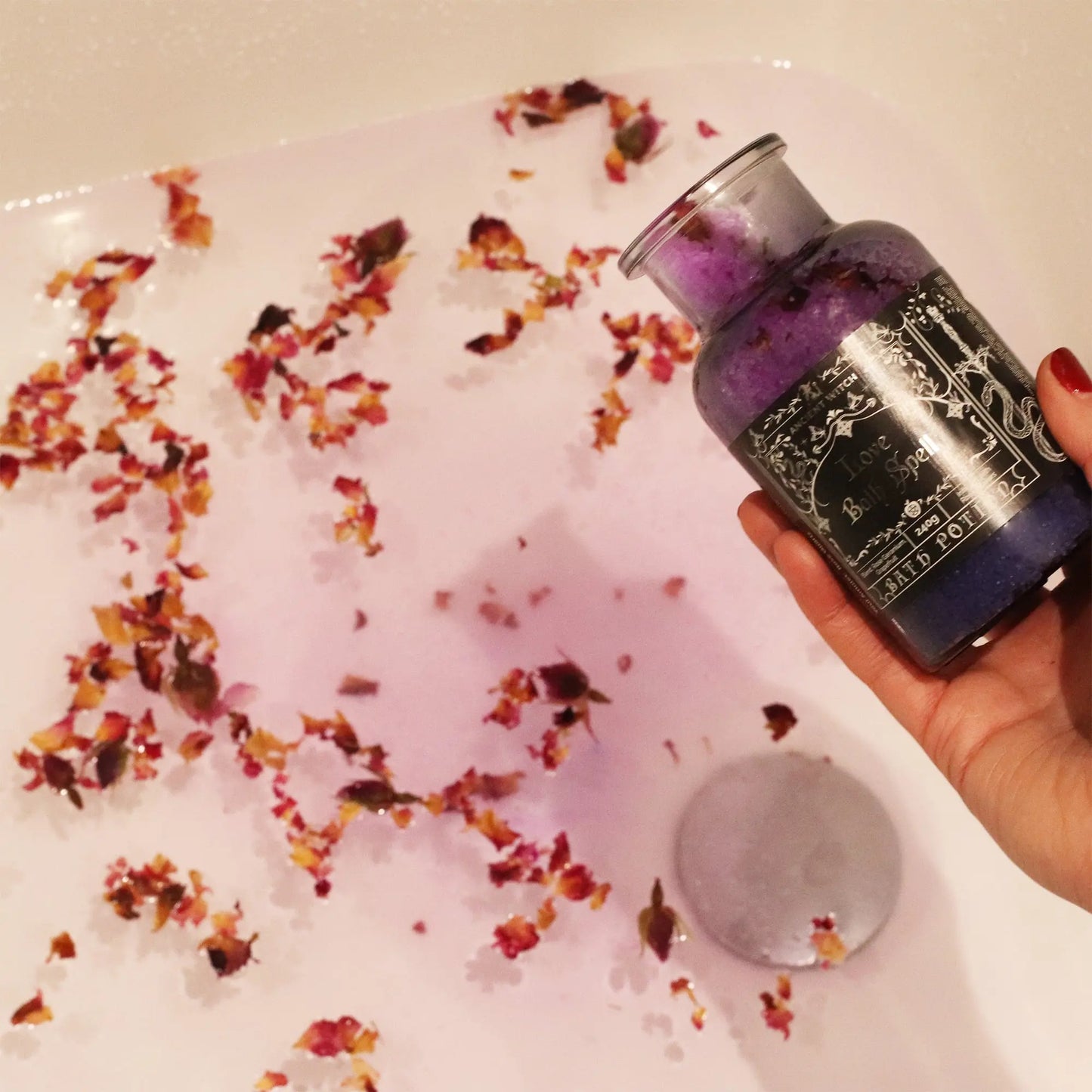 Bottle of purple bath product with floral petals in a bathtub