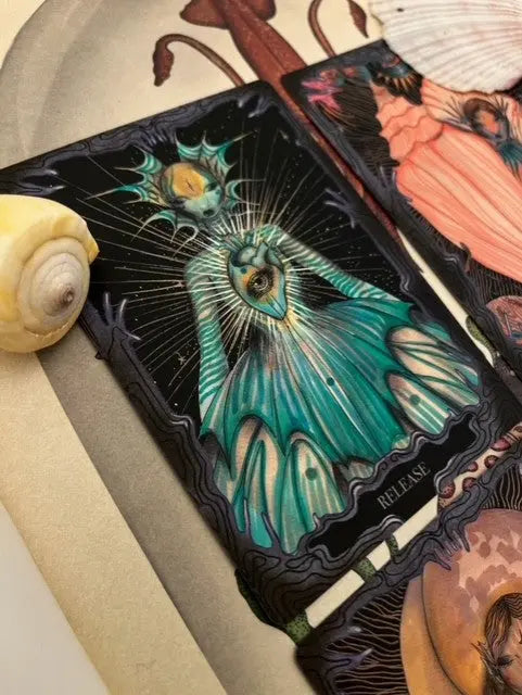 Colorful tarot card with a detailed design on a textured surface. Oracle card from the mermaids purse oracle titled Release