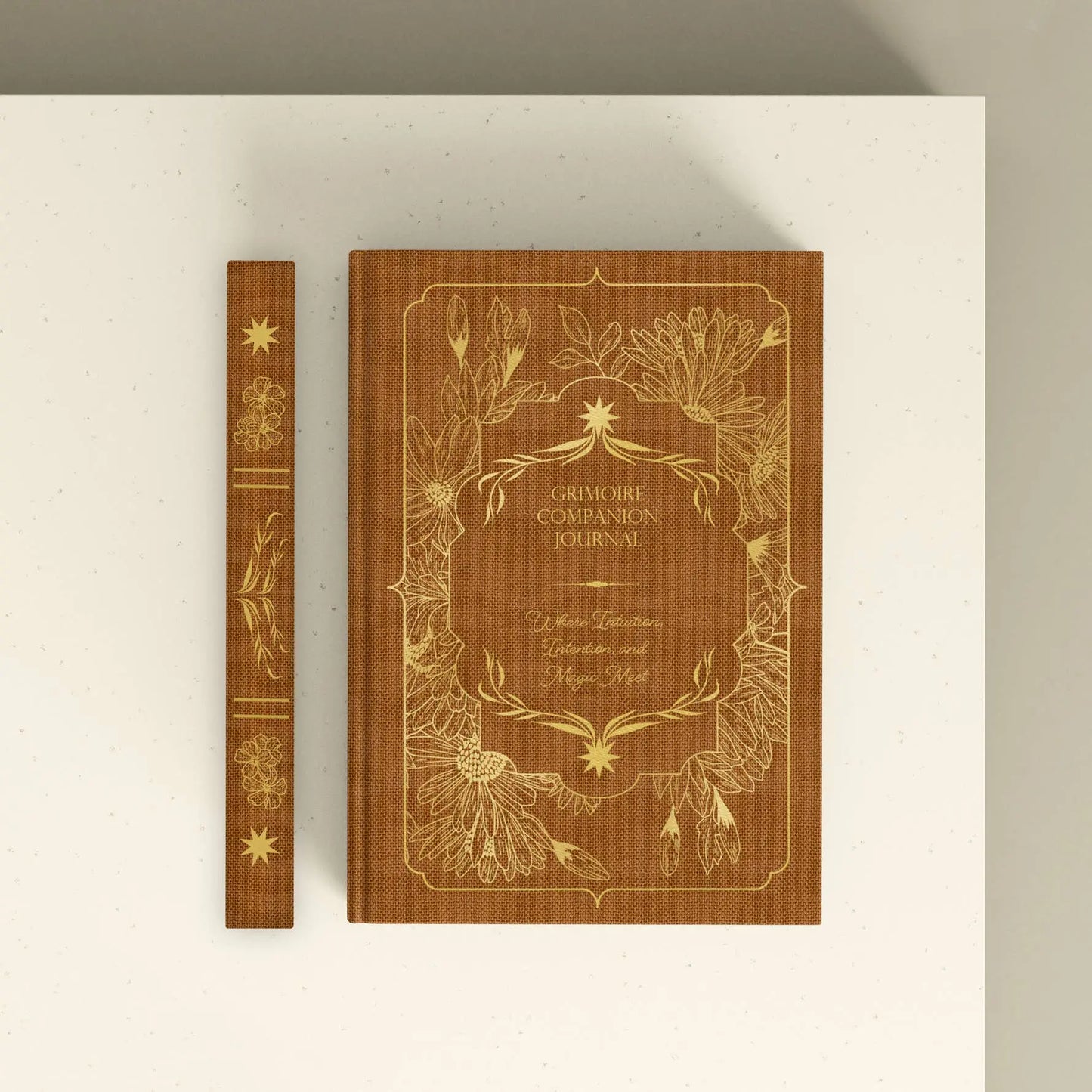 Brown journal with gold embossed design on a white surface Grimoire Bouchette and Co Oneness Emporium