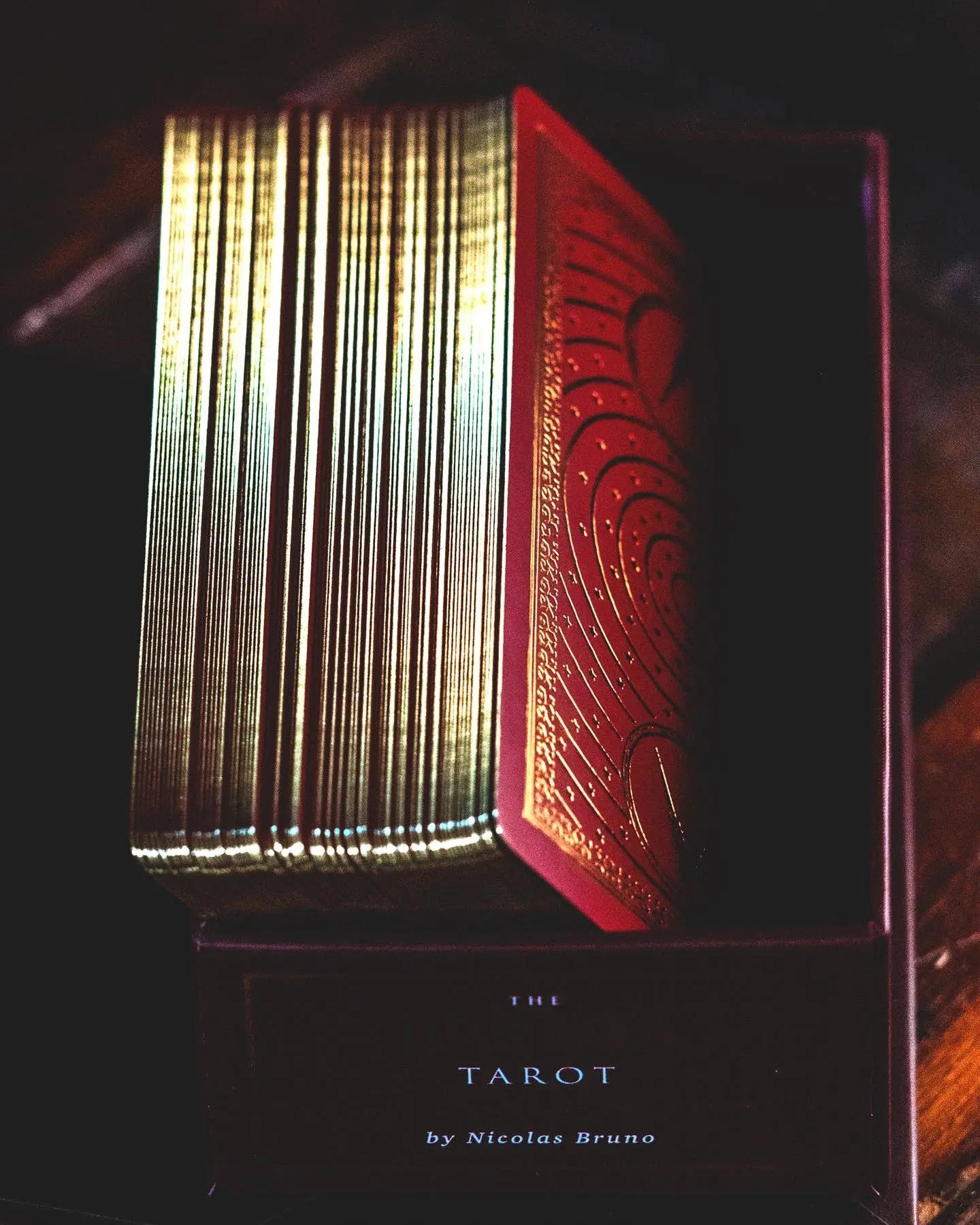 Red and gold tarot card book with 'Nicolas Bruno' branding on a dark background