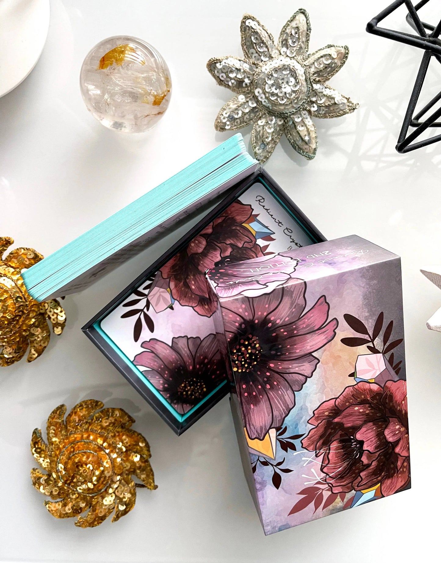 Floral-themed product packaging with decorative brooches on a white surface