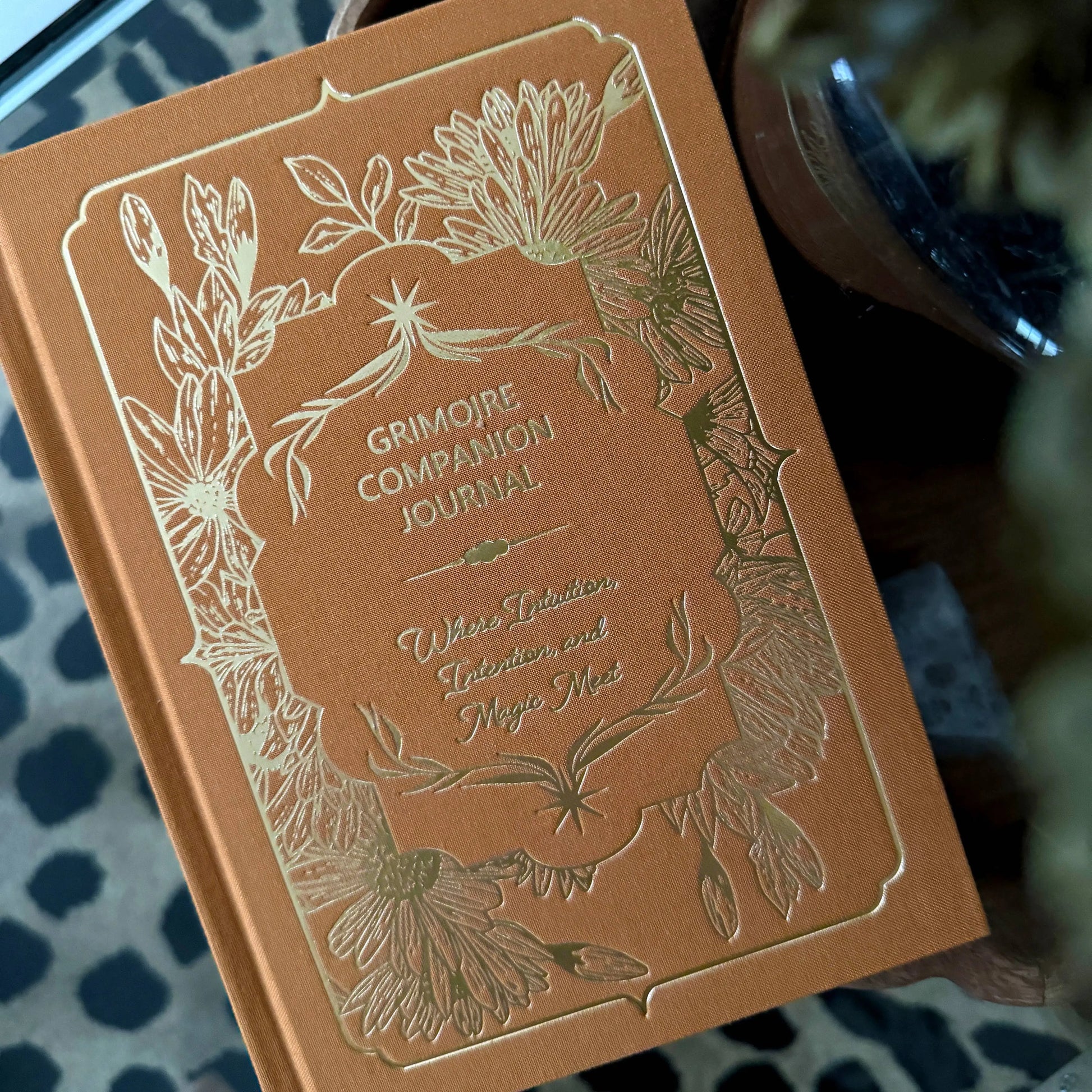 Brown journal with floral designs and text on a textured surface Grimoire Bouchette and Co Oneness Emporium