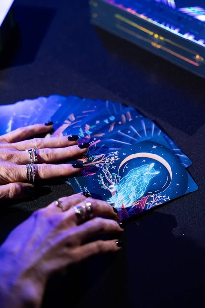 Hands with rings on tarot cards under a blue light