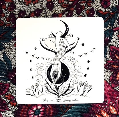 Tarot card with a black and white illustration of a woman and moon on a colorful floral background Dark Days Tarot by Wren McMurdo Brignac featuring square black-and-white tarot cards inspired by the lunar cycle with a 180-page guidebook and collector's box.