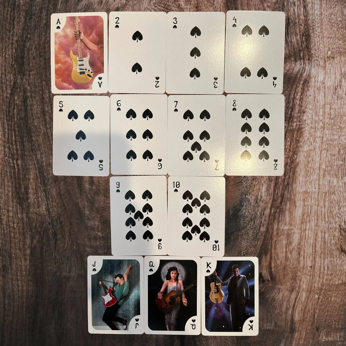 Playing cards with guitar-themed artwork on a wooden surface