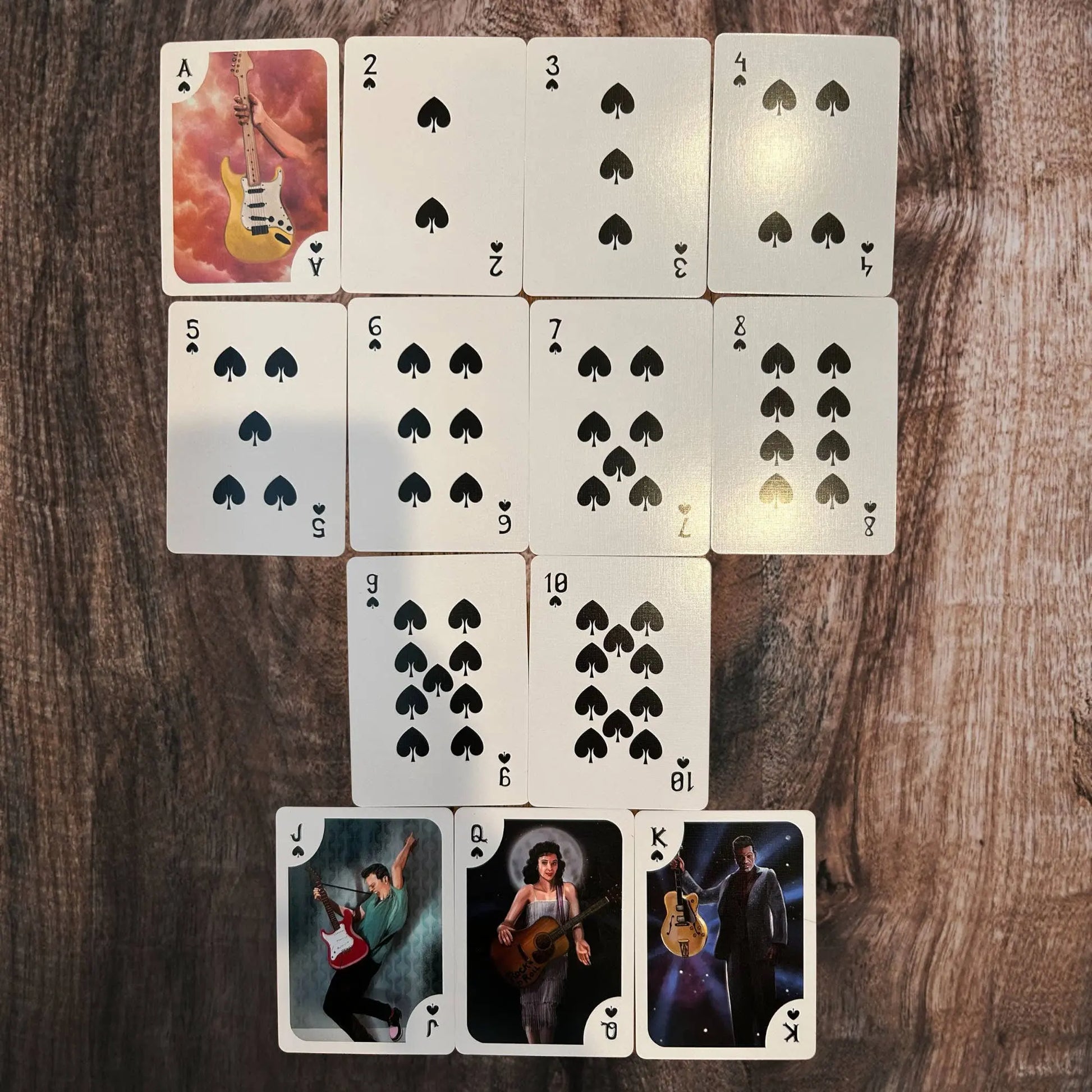 Playing cards with guitar-themed artwork on a wooden surface