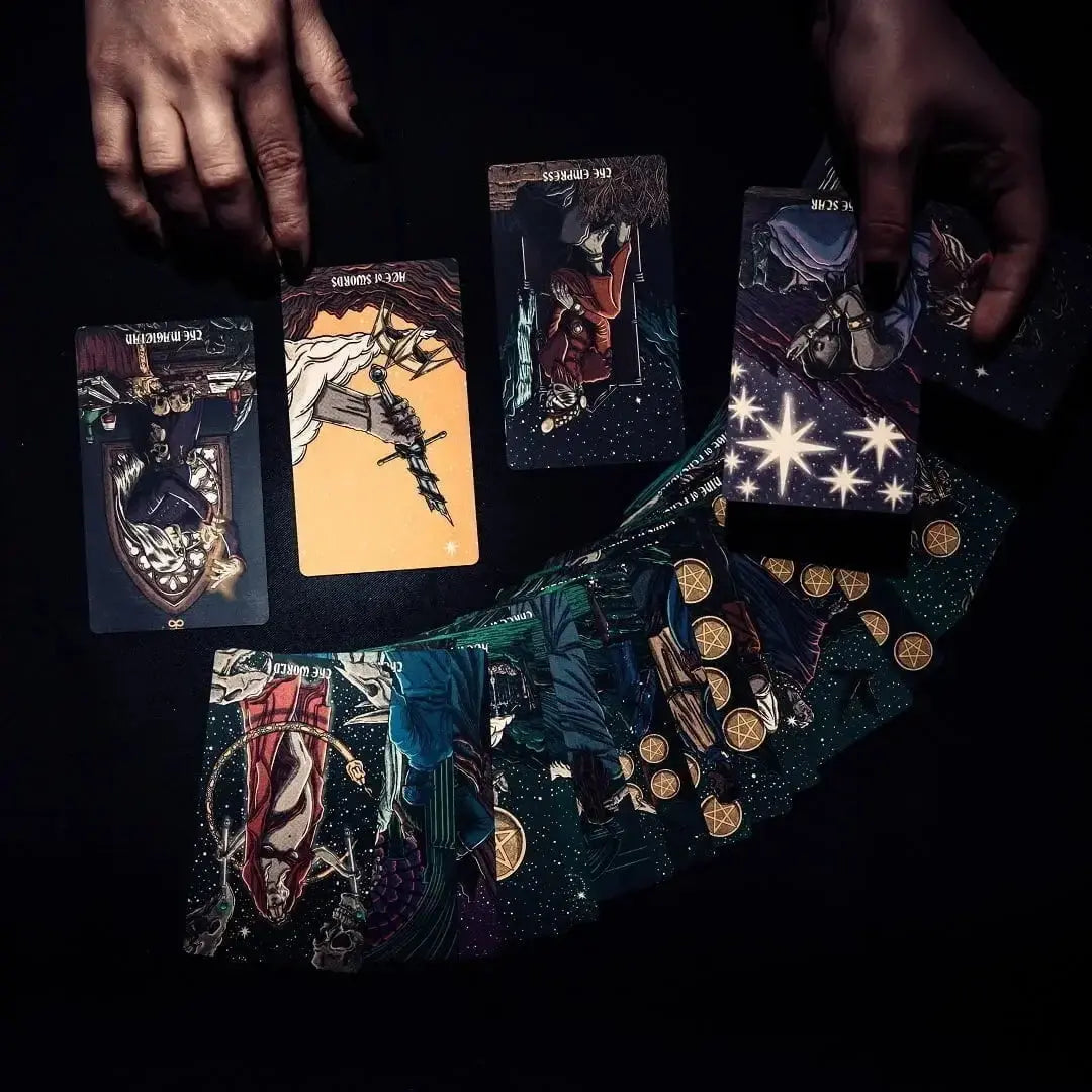 Collection of tarot cards on a dark surface with hands holding some cards. Dark reflections tarot by La Muci Available at Oneness Emporium