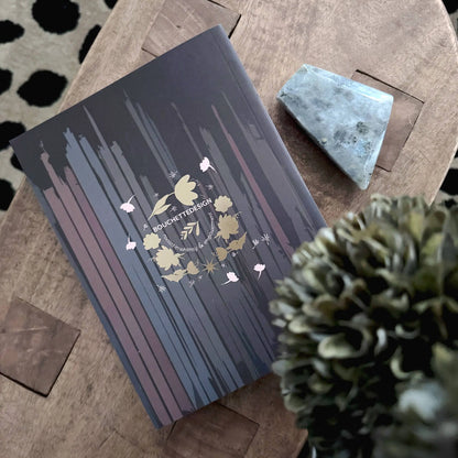 Decorative box with floral design on a wooden surface with a pine cone. Meraki workbook for tarot and crystal work 