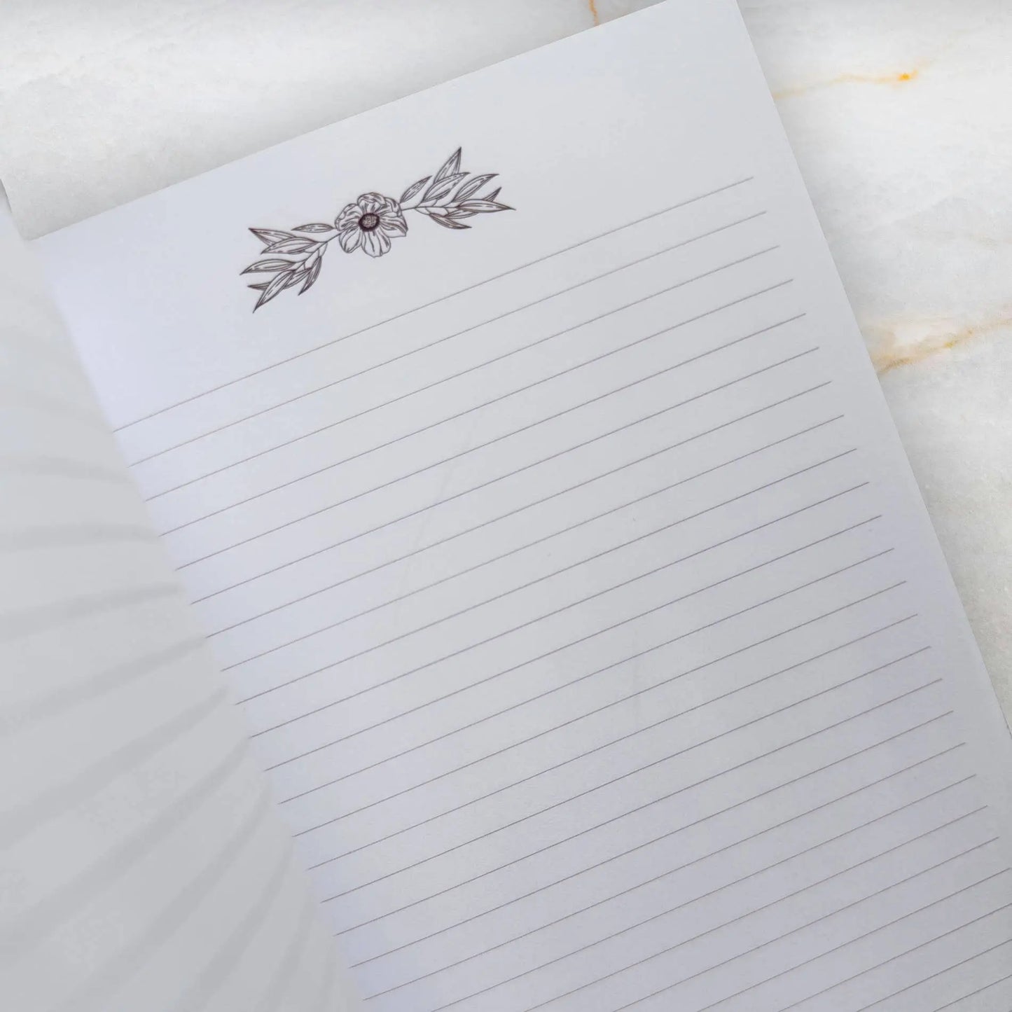 Notebook with floral design on the cover on a marble surface Meraki workbook for tarot and crystal work 
