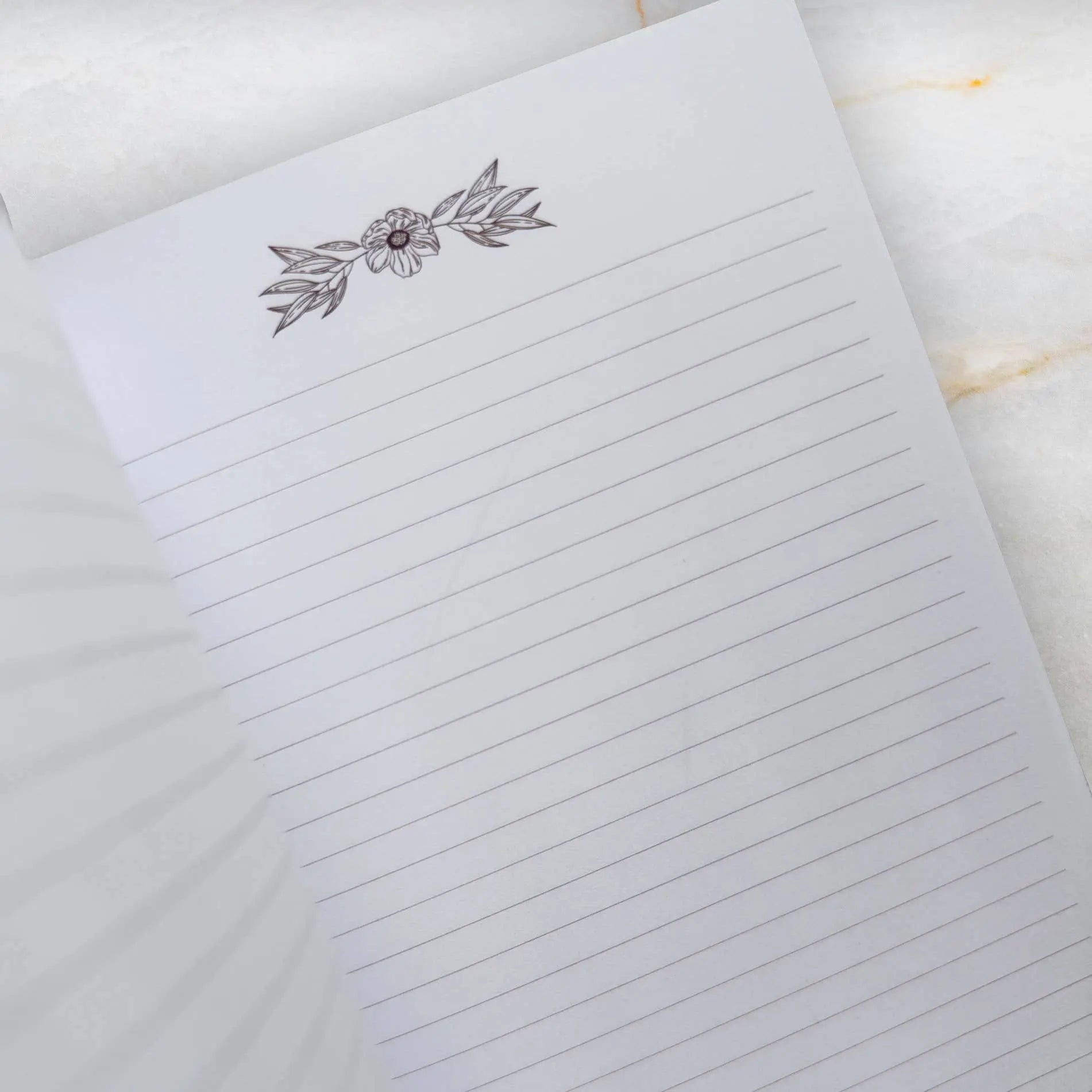 Notebook with floral design on the cover on a marble surface Meraki workbook for tarot and crystal work 