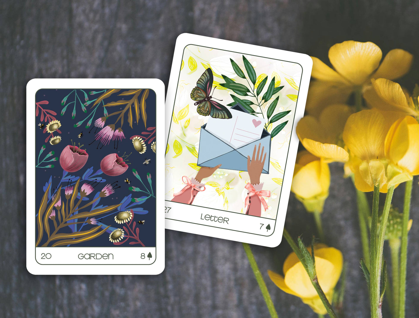 Two tarot cards with floral and butterfly designs on a dark surface with yellow flowers.