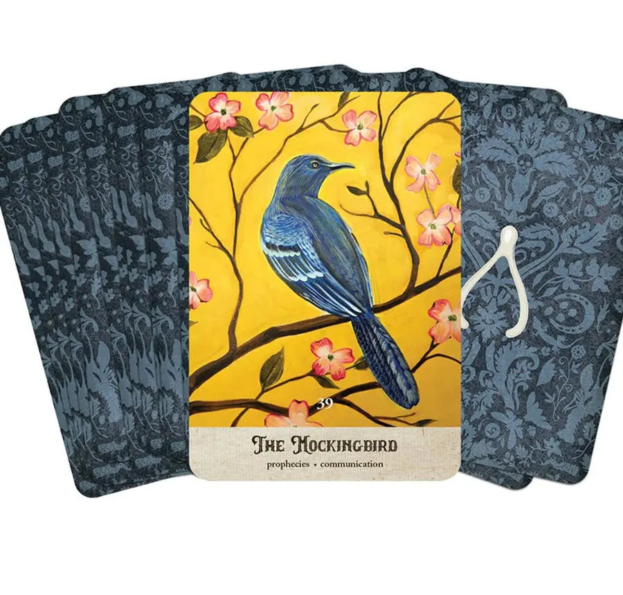 Card with a blue bird illustration on a yellow background, surrounded by floral elements, with patterned black cards on either side.