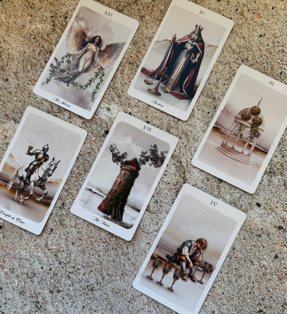 Five illustrated tarot-style cards arranged on a textured stone surface. The cards show vintage fantasy and historical scenes with figures, a horse, a tower, and a seated figure, and the card numbers are visible at the top.