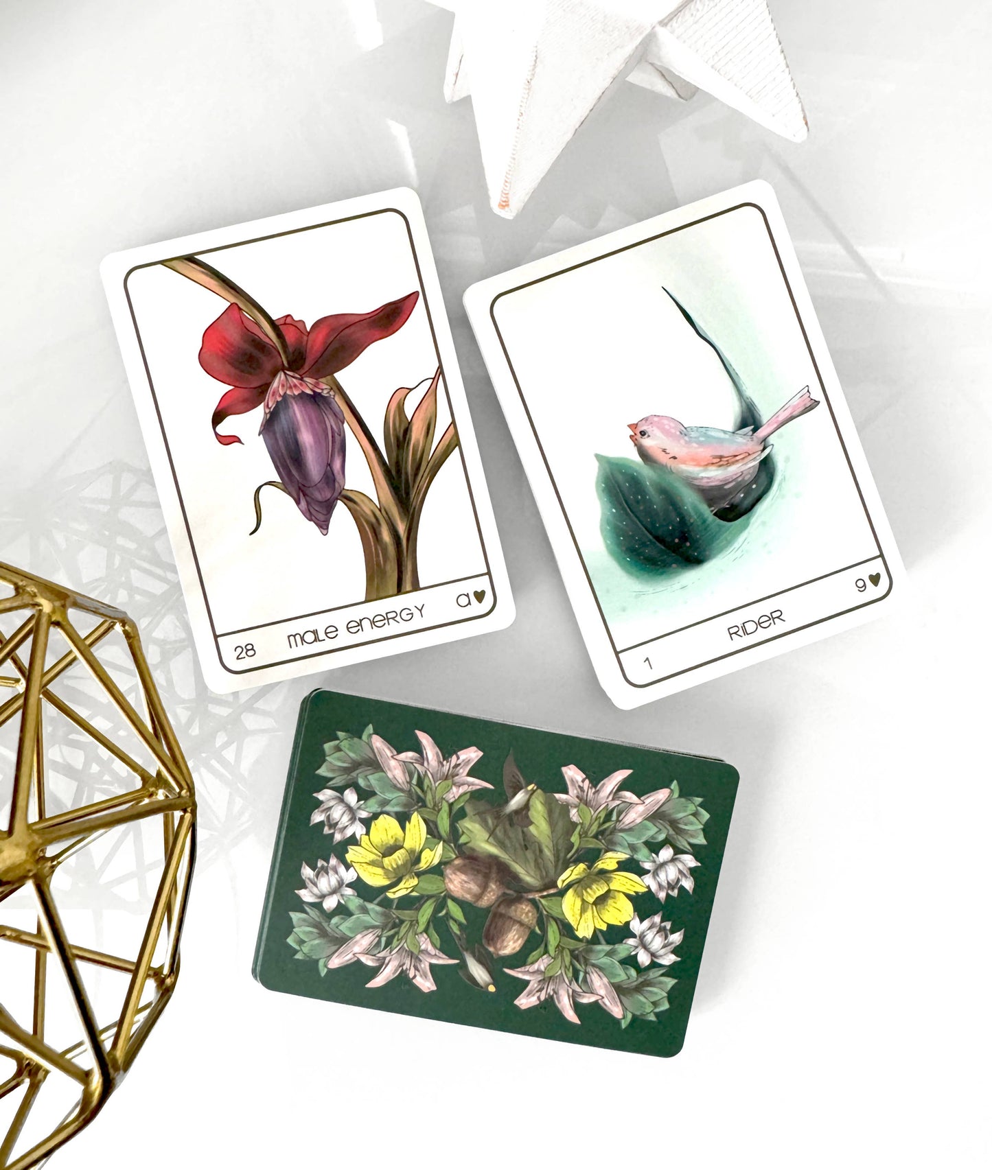 Three tarot cards with floral and nature-themed designs on a white surface.