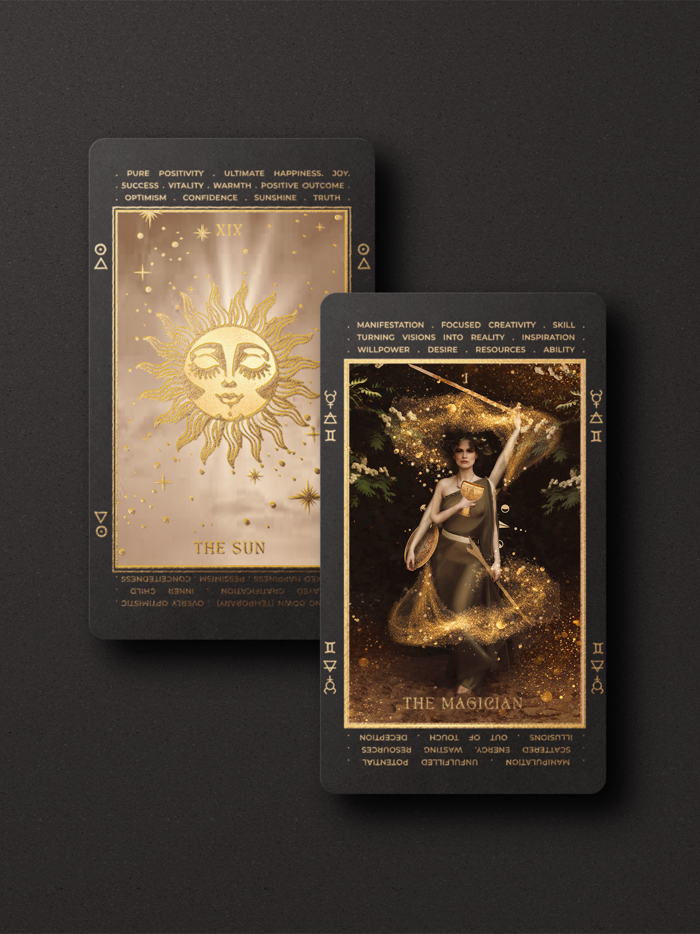 Two tarot cards displayed on a dark background, featuring gold and black designs with celestial and mystical imagery. One card shows a golden sun face, and the other depicts a magical figure surrounded by glowing light.