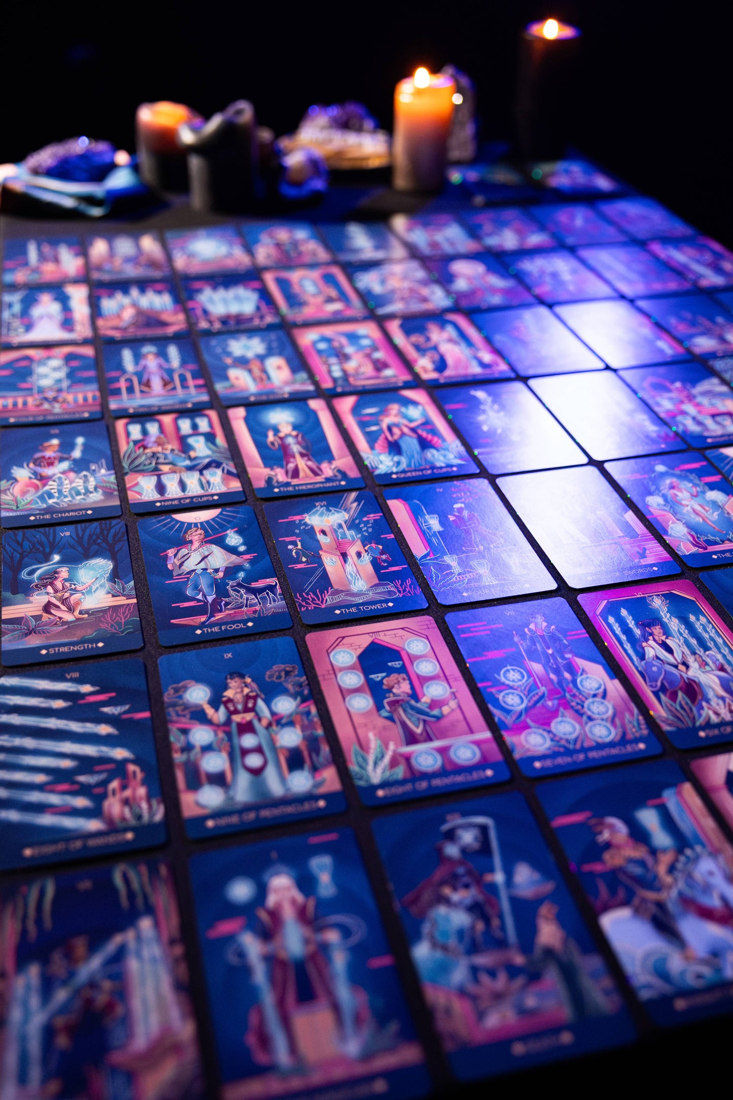 Collection of colorful tarot cards on a dark surface with candles