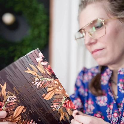 Person holding a makeup palette with floral design, blurred background Meraki workbook for tarot and crystal work 