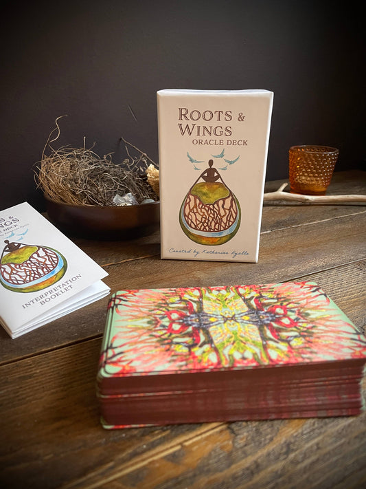 Oracle deck with 'Roots & Wings' packaging on a wooden surface