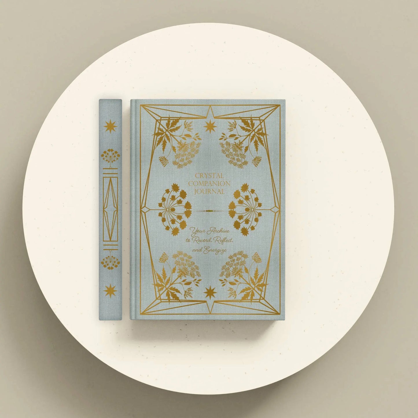 Decorative book with gold floral designs on a white platform Crystal companion journal by Bouchette and Co available from Oneness Emporium