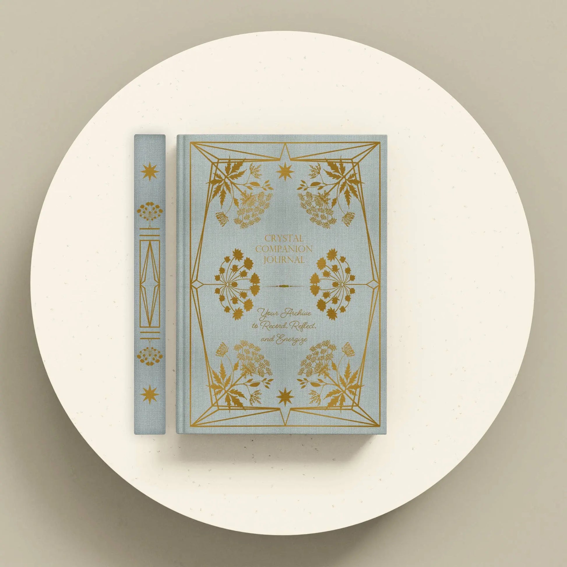 Decorative book with gold floral designs on a white platform Crystal companion journal by Bouchette and Co available from Oneness Emporium