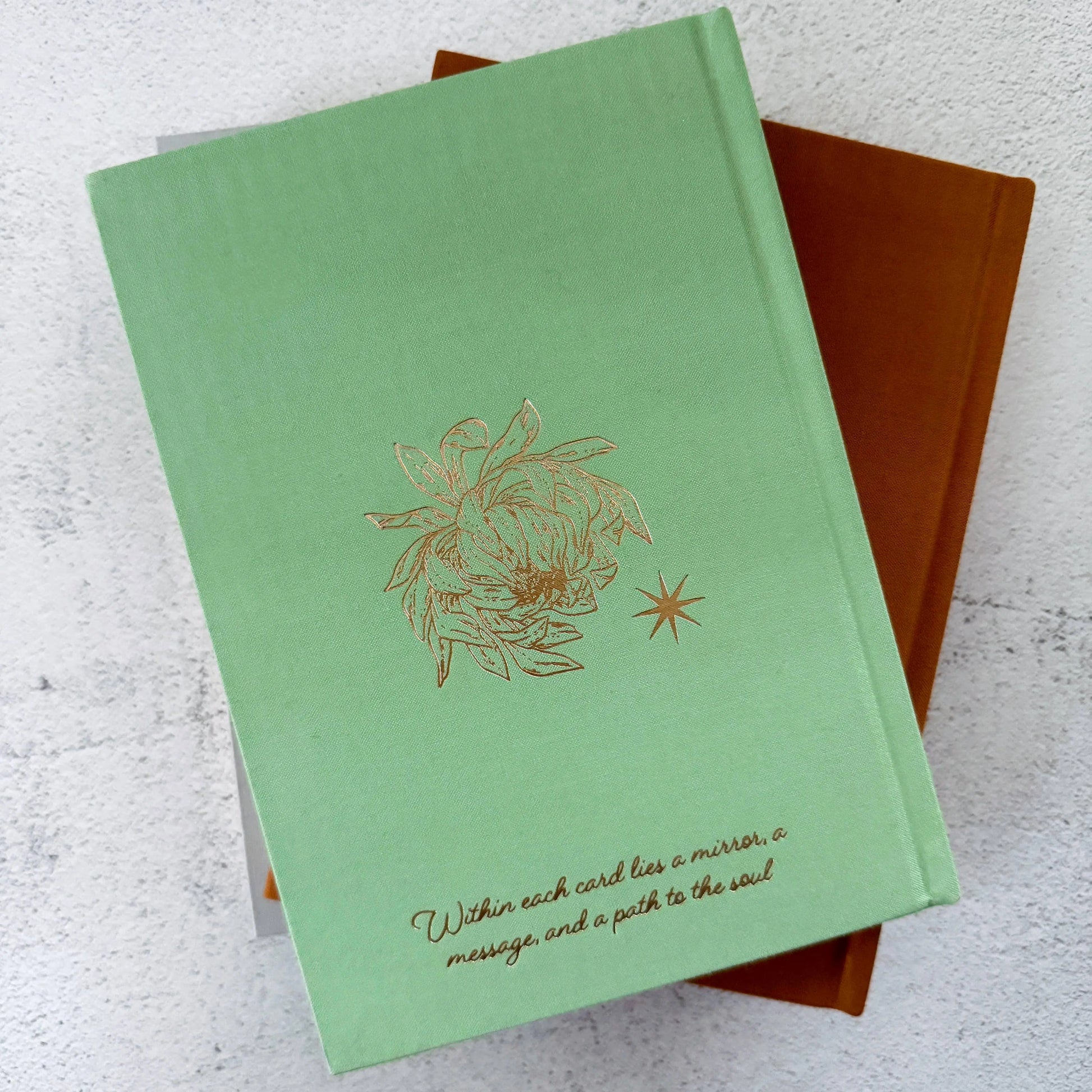 Green card with gold design and text on a textured surface Tarot Journal Bouchette and Co Oneness Emporium