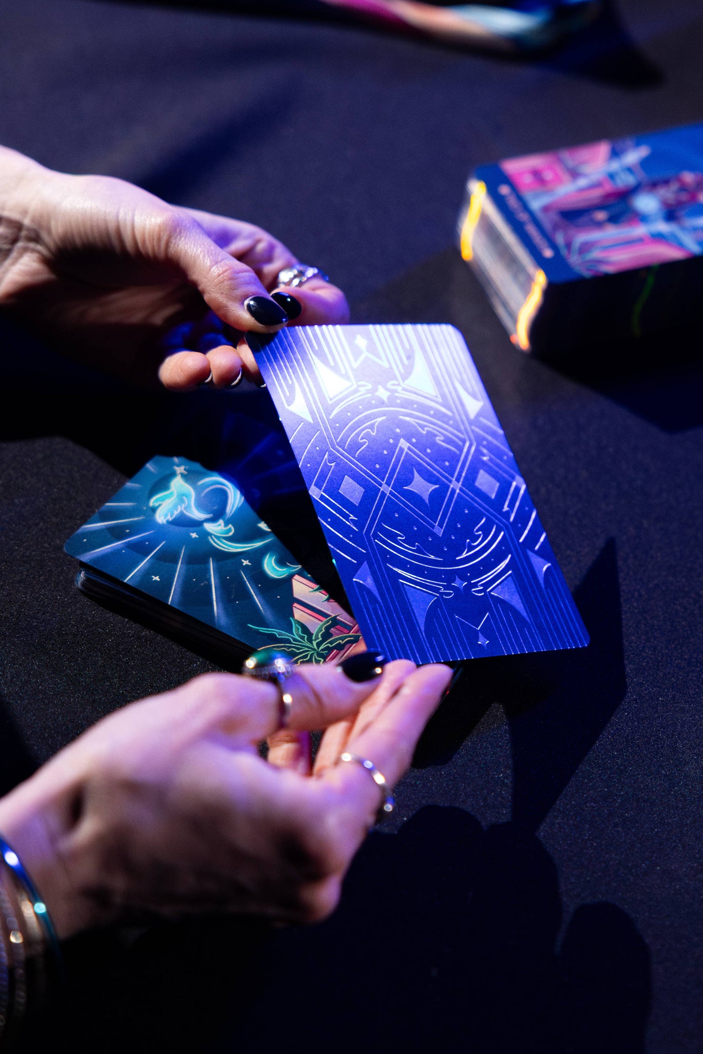 Close-up of hands holding tarot cards on a dark surface