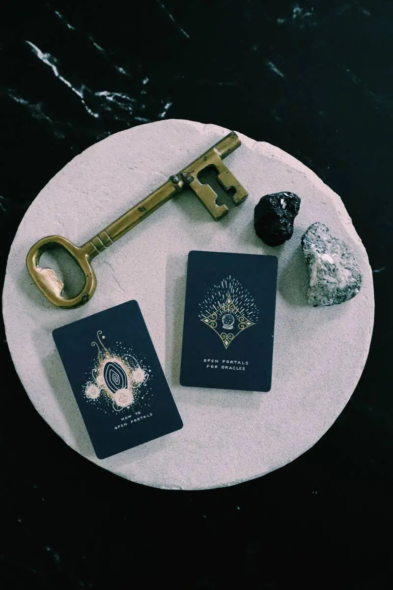 Decorative key, books, and stones on a round stone surface with a dark background