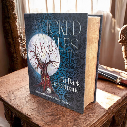 Book titled 'Wicked Wales: A Dark Lenormand' on a wooden surface with a blurred background