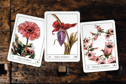 Three tarot cards with floral designs on a wooden surface